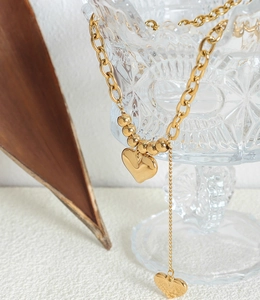 Vue détaillée du collier avec pendentif double cœur doré 18 carats et chaîne à maillons