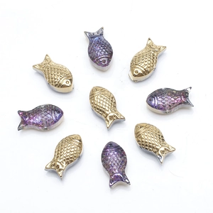 Detailed view of iridescent fish beads in gold and purple for DIY jewelry making
