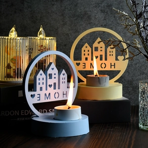 Gemütliches Deko-Set mit zwei hohlen Kerzenhaltern, HOME-Schriftzug und brennenden Teelichtern