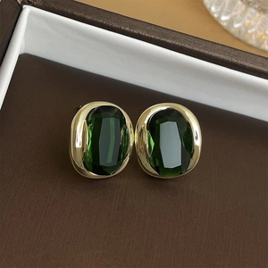 Detail view of oval emerald zircon earrings in gold plating inside a jewelry box