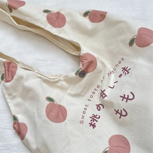 Detail of peach print canvas tote bag featuring button closure and graphic text
