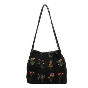 Black canvas tote bag with colorful wildflower floral embroidery and dual shoulder straps