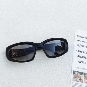 Detail view of black oval sports sunglasses with plastic frames on a textured white surface