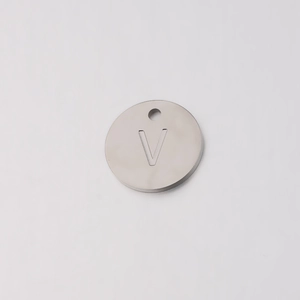 Macro shot of mirror-polished silver stainless steel 12mm round pendant with engraved V