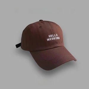 Detail of HELLO WEEKEND white embroidery on a dark brown cotton baseball cap
