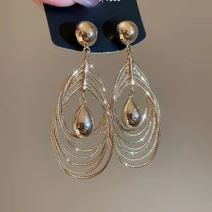 Detail view of multi-layer teardrop metal earrings with 18k gold plating and polished finish