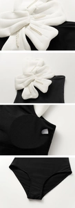Detail of black one-piece swimsuit featuring 3D white bow with pearls and removable pads