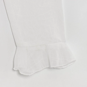 Close-up of white long sleeve shirt cuff with elegant ruffled edge and linen texture
