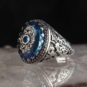 Detail of vintage men's ring featuring blue gemstone and intricate engraved silver band