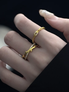 Detail of minimalist gold-plated crossover branch ring and geometric diamond-set band