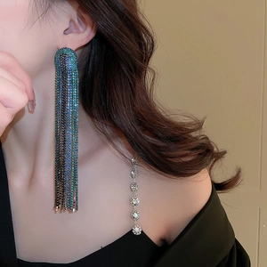 Detailed close-up of long geometric tassel earrings with blue rhinestones on a model