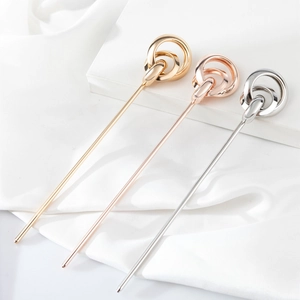 Close-up of gold, rose gold, and silver metal hair pins on white silk fabric background