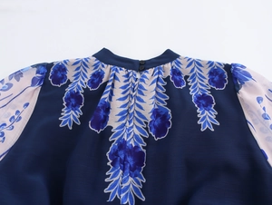 Close-up of high neck stand collar with double button fasteners on navy floral blouse