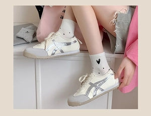Close-up of retro cream sneakers with silver stripes styled with pink bow accent socks