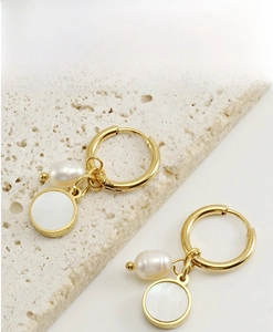 Detail shot of pearl shell earrings with 18K gold plating on a stone background
