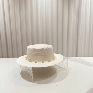 Détail du tissage et du ruban orné de perles sur un chapeau de paille blanc élégant