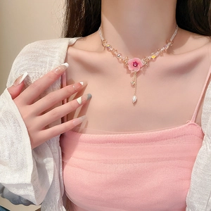Elegant necklace with pink floral pendant and champagne bead tassels worn by a model