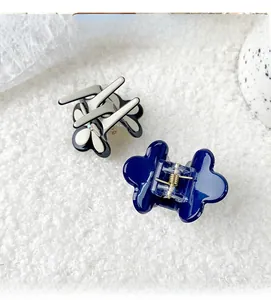 Détail de mini pinces à cheveux en fleur d'acétate avec cristaux sur fond en peluche douce