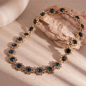 Detail of vintage gold flower link necklace with dark blue gems and sparkling crystals