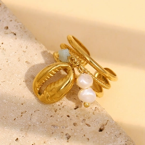 Detail of 18K gold plated layered ring with shell charm and white pearls on stone