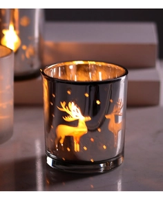 Close-up of silver plated glass candle holder with reindeer and star cutout patterns
