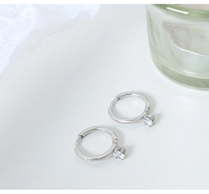 Detail of silver hoop earrings with sparkling round zircon pendants on white background
