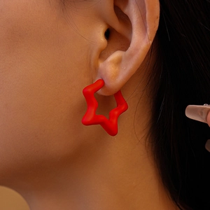Close-up of a matte red star-shaped earring worn on ear for minimalist style