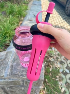 Detail of pink plastic tea tumbler showing black lid with silicone filter and tea infuser