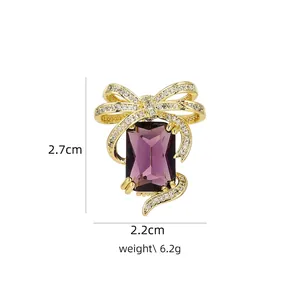 Detail view of purple crystal brooch with gold bow and dimensions 2.7cm by 2.2cm