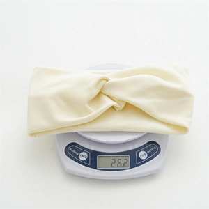 Detailed view of cream fabric headband on digital scale showing its light weight of 26.2g