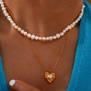 Layered gold stainless steel necklace featuring freshwater pearls and a textured heart pendant