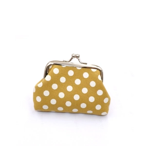 Detailed view of ginger yellow canvas coin purse with white polka dots and silver clasp