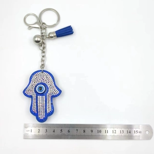 Detail shot of Hamsa hand evil eye keychain with blue tassels and size measurements
