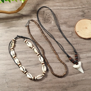 Close-up of layered ocean-style necklaces with shell, shark tooth and coconut wood