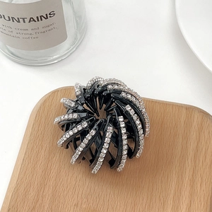 Détail de la pince à cheveux nid d'oiseau avec strass sur un plateau en bois