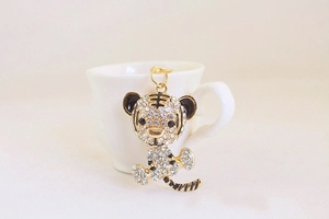 Detail of a gold tiger keychain with sparkling rhinestones and black enamel accents