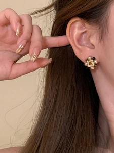 Nahaufnahme von Vintage-Blumenohrringen mit Perlen und Goldbasis am Ohr eines Modells