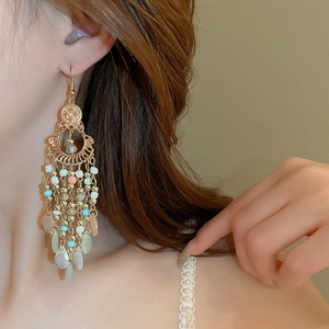 Close-up of bohemian beaded tassel earrings with crystal drops worn by a model