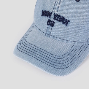 Detailed close-up of 3D New York embroidery and texture on blue denim baseball cap