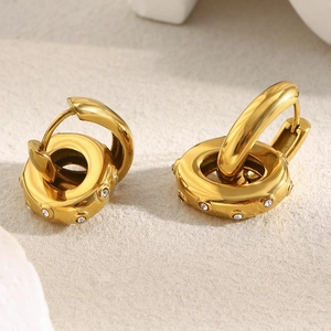 Detail of gold-plated hoop earrings featuring oval zircon pendants and crystal textures