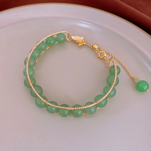 Detail of handmade beaded bracelet with green round beads and gold wire wrapping craft