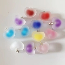 Macro shot of colorful matte heart pendants with silver metal hooks on white background