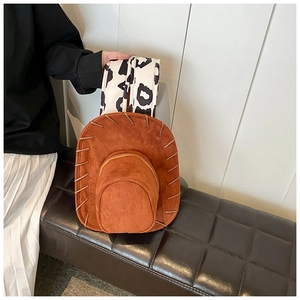 Detail of a brown suede cowboy hat bag featuring stitched edges and leopard print strap