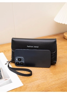 Dettaglio della pochette in finta pelle nera con stampa Fashion Trend e cinturino da polso