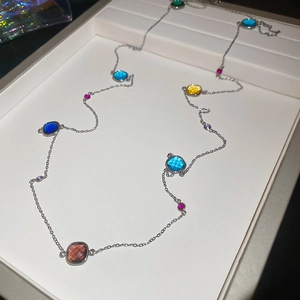 Close-up of long silver chain necklace with multi-colored square and round crystals
