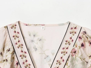 Detail shot of a floral linen-blend top neckline with size S label and pink pattern