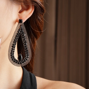 Macro detail of gothic black teardrop earring featuring dark metal mesh and crystals