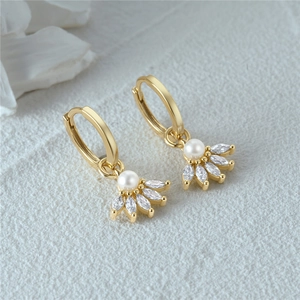 Macro shot of gold hoop earrings with white pearls and marquise-cut zircons in flower design