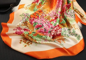 Detailed view of colorful floral satin square scarf with orange borders and silk-like shine