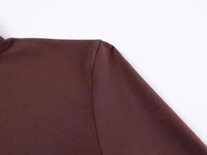 Detailed close-up of dark brown knitted fabric showing shoulder seams and soft texture